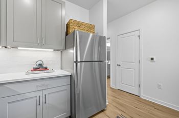 A kitchen with a refrigerator, cabinets, and a countertop.